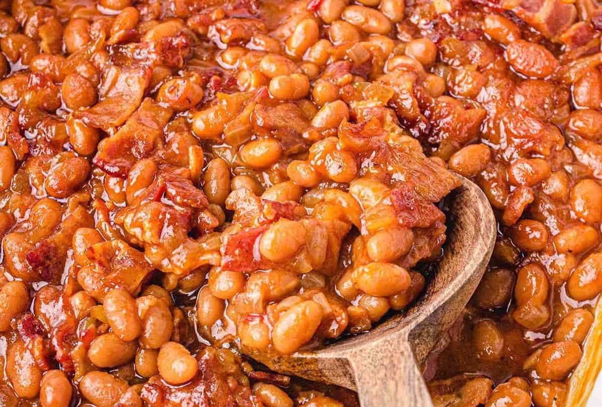 Closeup picture of baked beans with wooden spoon.